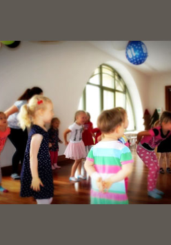 Częściowo nieostre zdjęcie z zajęć Strefa Zabawy. Roztańczone dzieci bawią się pod opieką instruktorki.