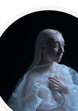 Na zdjęciu artystka w błękitnej sukni na czarnym tle.