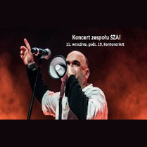 Wokalista w trakcie koncertu. W tle biały napis z datą wydarzenia.