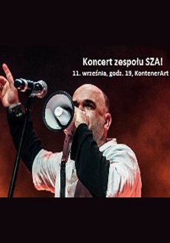 Wokalista w trakcie koncertu. W tle biały napis z datą wydarzenia.