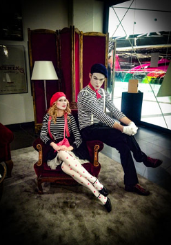 Fotografia ze spektaklu "Lekcja Pantomimy" Teatru HoM, Tychy. Na pierwszym planie mim Pierrot i aktorka dramatyczna Zosia. Aktorzy siedzą na fotelu, patrząc w kierunku fotografa.