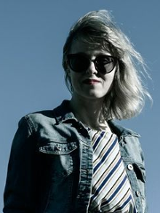 Na zdjęciu artystka w ciemnych okularach na tle błękitnego nieba.