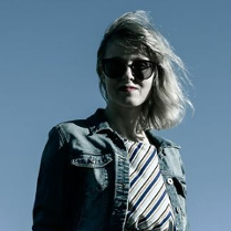Na zdjęciu artystka w ciemnych okularach na tle błękitnego nieba.