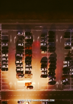 Parking z lotu ptaka, na nim samochody skierowane w stronę ekranu, na którym wyświetla się film.