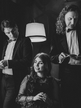 Dwójka mężczyzn trzyma książki. Między nimi siedzi kobieta.