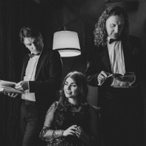 Dwójka mężczyzn trzyma książki. Między nimi siedzi kobieta.