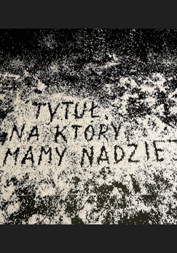 Na czarnym podłożu został ułożony napis z rozsunięcia białych drobin: "Tytuł, na który mamy nadzieję".