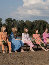 Na zdjęciu członkinie zespołu siedzące na krzesłach na plaży.