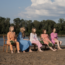 Na zdjęciu członkinie zespołu siedzące na krzesłach na plaży.