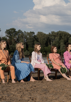 Na zdjęciu członkinie zespołu siedzące na krzesłach na plaży.