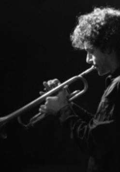 Na czarno-białym zdjęciu sylwetka trębacza.