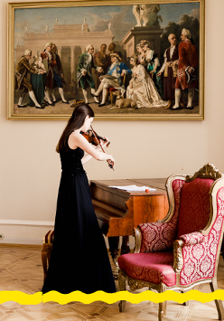 Na zdjęciu skrzypaczka stojąca przy fortepianie. Na ścianie obraz przedstawiający scenę z życia dworu.