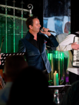 Na zdjęciu trzyosobowy zespół muzyczny na scenie.