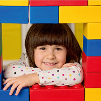 Zdjęcie dziewczynki chowającej się za budowlą z klocków