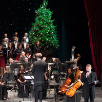 Na zdjęciu scena z operze poznańskiej z orkiestrą i choinką na środku.