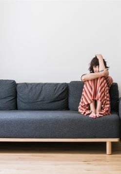 Na zdjęciu artystka siedząca na sofie.