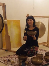 zdjęcie kobiety trzymającej misę; w tle gongi