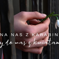 Na zdjęciu ręce z przebiśniegiem wystające zza krat. Na nadgarstku lewej ręki biało-czerwono-biała opaska.