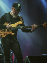 Na zdjęciu artysta stojący na scenie z gitarą.