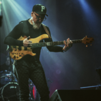 Na zdjęciu artysta stojący na scenie z gitarą.