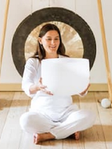 zdjęcie kobiety siedzącej po turecku; w rękach trzyma białą misę