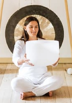 zdjęcie kobiety siedzącej po turecku; w rękach trzyma białą misę