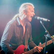 Na zdjęciu Andy Egert z gitarą śpiewa do mikrofonu.