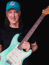 Na zdjęciu artysta z gitarą.