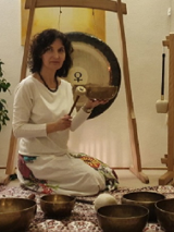 Kobieta trzymająca w ręku misę. W tle widoczny gong.