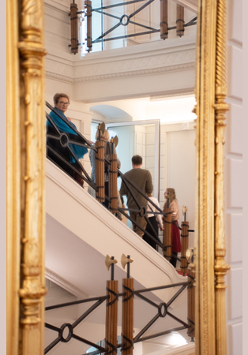 Grupa ludzi stoi na schodach Biblioteki i słucha przewodniczki.
