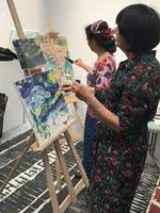 Dwie kobiety malujące obrazy na sztalugach.