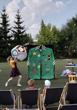 Kobieta i mężczyzna rzucający wielką kostką szcześcienną podczas zabawiania dzieci.