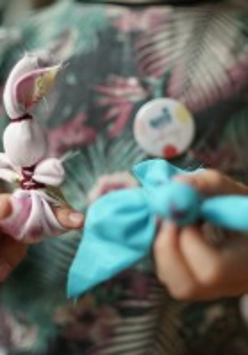 Zdjęcie dziecka trzymającego dwie motanki, niebieską i różową.