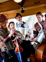 Zdjęcie członków zespołu grających wewnątrz starego tramwaju.