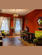 Wnętrze Muzeum: salon z antycznymi meblami i ciemnoczerwonymi ścianami.