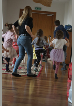 Na zdjęciu znajduje się grupa dzieci razem z prowadzącą warsztaty taneczne.