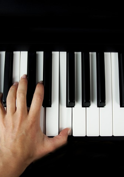 Dłoń na klawiszach fortepianu.