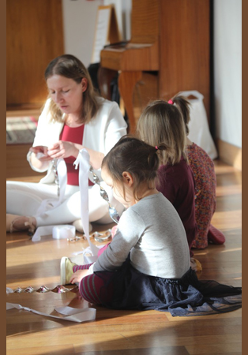 Zdjęcie przedstawia grupę małych dzieci na warsztatach wraz z prowadzącą.