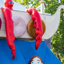 Zdjęcia maskotki ze spektaklu. Imitacja dziecka w wodzie, a obok na białej łodzi kraken.