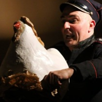 Zdjęcie aktora z białą kurą w trakcie spektaklu.