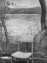 Czarno-biała fotografia przedstawia krzesło stojące na ziemi porośniętej trawą