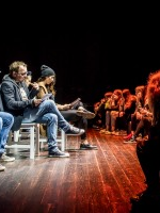 Na zdjęciu fragment przedstawienia. Na scenie, twarzami do widzów, na krzesłach siedzą aktorzy, czytają.