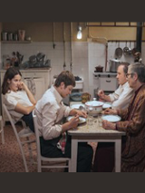 Kadr z filmu. Czworo ludzi siedzi przy stole w kuchni: dwóch mężczyzn, chłopak i dziewczyna.