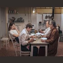 Kadr z filmu. Czworo ludzi siedzi przy stole w kuchni: dwóch mężczyzn, chłopak i dziewczyna.