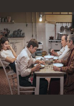 Kadr z filmu. Czworo ludzi siedzi przy stole w kuchni: dwóch mężczyzn, chłopak i dziewczyna.