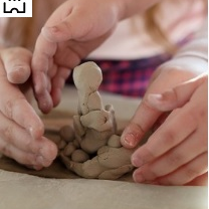 dziecięce i dorosłe dłonie ujęte podczas lepienia pracy z gliny.