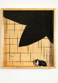 w kwadratowym obrazie z prostopadła ramą jest postawiony czarnobialy kot, tlo jest bezowe z czarnym duzym fragmentem jakby liścia