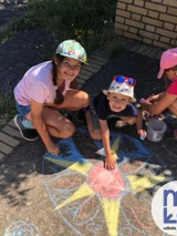 uismiechnięte dzieci przy rysunku wykonanym kredą na ziemi