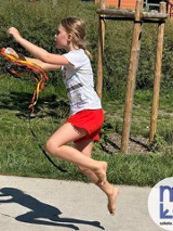 dziewczynka, która wykonuje skok z kolorowymi wstążkami w ręku w plenerze