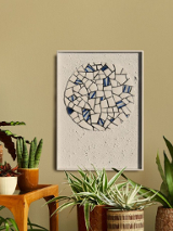 okragła mozaika z białych i niebieskich elementów w ramce zawieszona na ścianie